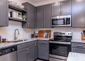 Thumbnail 8 of 30 - A kitchen with dark grey cabinets and stainless steel appliances.