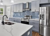 Thumbnail 18 of 33 - A modern kitchen with a stainless steel refrigerator and a marble countertop.
