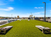 Thumbnail 15 of 31 - A grassy area with benches and a fence in the background.