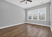 Thumbnail 22 of 33 - A room with a ceiling fan and wooden flooring.