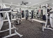 Thumbnail 14 of 25 - A spacious gym with a variety of equipment including treadmills, weight machines, and benches.