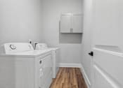 Thumbnail 21 of 33 - A white bathroom with a wooden floor and white cabinets.