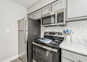 Thumbnail 2 of 16 - A kitchen with a stainless steel refrigerator, microwave, and oven.