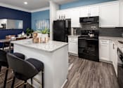 Thumbnail 3 of 25 - A kitchen with a black refrigerator and white cabinets.