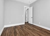 Thumbnail 26 of 33 - A room with a white door and wooden flooring.