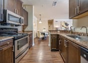 Thumbnail 2 of 29 - A kitchen with dark wood cabinets and a black stove top oven.