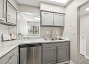 Thumbnail 3 of 16 - A kitchen with a stainless steel dishwasher and a white countertop.