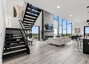 Thumbnail 18 of 35 - A modern living room with a staircase and a flat screen TV.