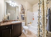 Thumbnail 8 of 29 - A bathroom with a brown counter top and a white toilet.