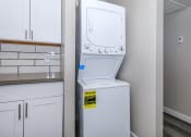 Thumbnail 11 of 22 - a white washer and dryer in a kitchen with white cabinets