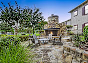 Thumbnail 15 of 28 - a patio with a stone fireplace and a table and chairs