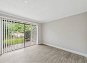 Thumbnail 5 of 16 - A room with a sliding glass door and wooden flooring.