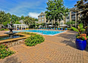 Thumbnail 18 of 25 - A pool surrounded by a brick patio and a fountain.
