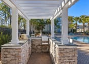 Thumbnail 24 of 30 - A patio with a stone wall and a grill.