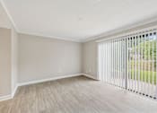 Thumbnail 4 of 16 - A room with a sliding glass door and wooden flooring.