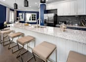 Thumbnail 4 of 25 - A kitchen with a white countertop and a black refrigerator.