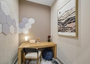 Thumbnail 21 of 26 - A room with a desk, chair, and a painting on the wall.