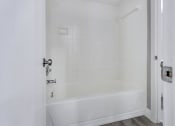 Thumbnail 17 of 33 - a white bathroom with a white tub and a white door