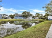 Thumbnail 30 of 33 - a pond with a fountain in front of a blue house