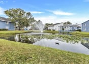 Thumbnail 29 of 33 - a pond with a fountain in the middle of some houses