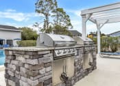 Thumbnail 23 of 33 - an outdoor kitchen with two stainless steel appliances and a grill