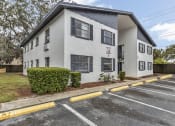 Thumbnail 27 of 29 - a white apartment building with a parking lot