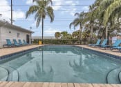 Thumbnail 26 of 29 - a pool with blue chairs and palm trees next to a house