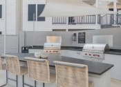 Thumbnail 16 of 29 - a kitchen with a bar with chairs and a grill