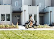 Thumbnail 25 of 26 - a man riding a scooter in front of an apartment building