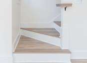 Thumbnail 14 of 26 - a small staircase in a home with white walls and wood floors