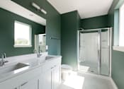 Thumbnail 21 of 26 - a bathroom with green walls and white cabinets