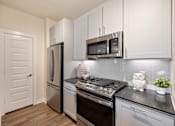 Thumbnail 2 of 33 - A kitchen with a stove top oven, microwave, and refrigerator.