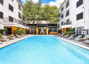 Thumbnail 21 of 37 - a swimming pool with chaise lounge chairs in front of an apartment building