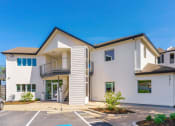 Thumbnail 27 of 29 - a white building with a balcony and a parking lot