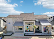 Thumbnail 1 of 40 - A house with a grey roof and a white wall with a black awning.