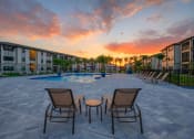 Thumbnail 22 of 23 - an outdoor patio area with chairs and a pool at sunset
