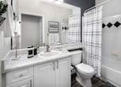 Thumbnail 11 of 25 - A white bathroom with a sink, toilet, and shower.