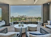 Thumbnail 24 of 29 - A balcony with a table and chairs overlooking a city skyline.