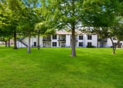 Thumbnail 17 of 28 - a grassy area with trees in front of a building