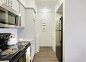 Thumbnail 10 of 40 - A kitchen with a black stove top oven and a black microwave above it.