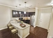Thumbnail 27 of 35 - A kitchen with a granite countertop and stainless steel appliances.
