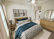 Thumbnail 29 of 35 - A bedroom with a bed, nightstand, and a dresser with a mirror.