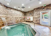 Thumbnail 17 of 62 - a indoor pool with a waterfall in a building with a glass door