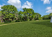 Thumbnail 37 of 62 - a large grassy field with trees and a building on the side