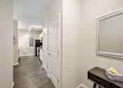 Thumbnail 42 of 42 - A hallway with a mirror on the wall and a table with a flower on it.