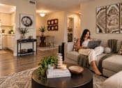 Thumbnail 4 of 52 - A woman is sitting on a couch using a laptop in a well-lit living room.