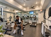 Thumbnail 3 of 52 - A man is working out in a gym with a variety of equipment.