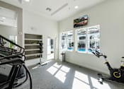 Thumbnail 8 of 40 - A gym with a treadmill, exercise bike and windows.