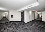 Thumbnail 20 of 40 - A long hallway with a carpeted floor and white walls.
