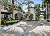 Thumbnail 12 of 40 - A sunny day at a courtyard with a white arched building and palm trees.